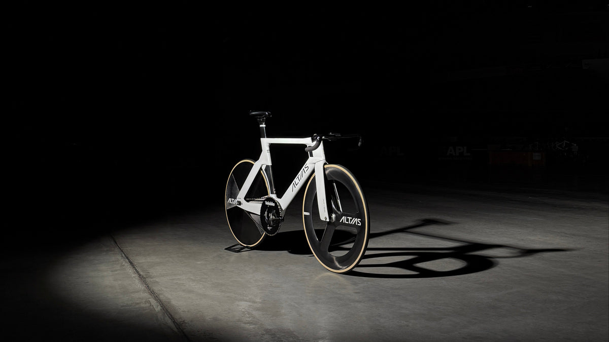 White track bike on a moody lit setting with a concrete floor