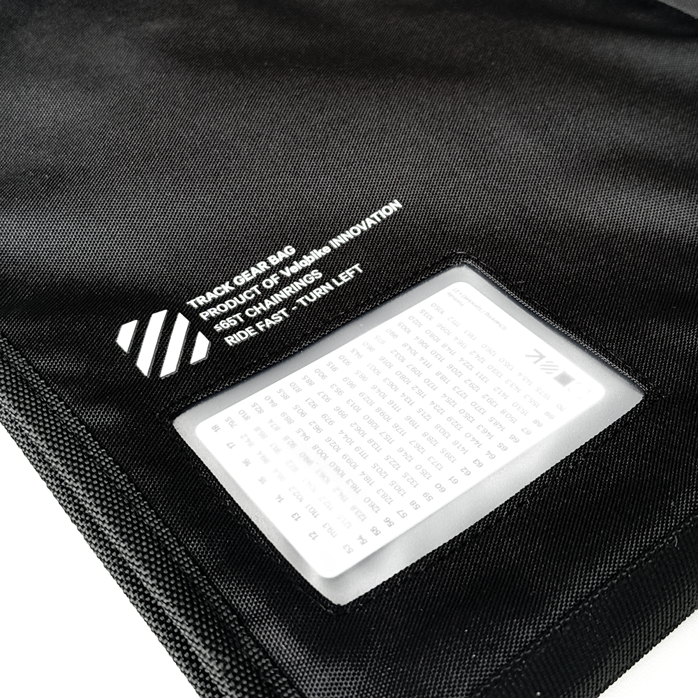 Close-up of a black track over bag with a clear plastic window showing a white insert sheet, on a white background.
