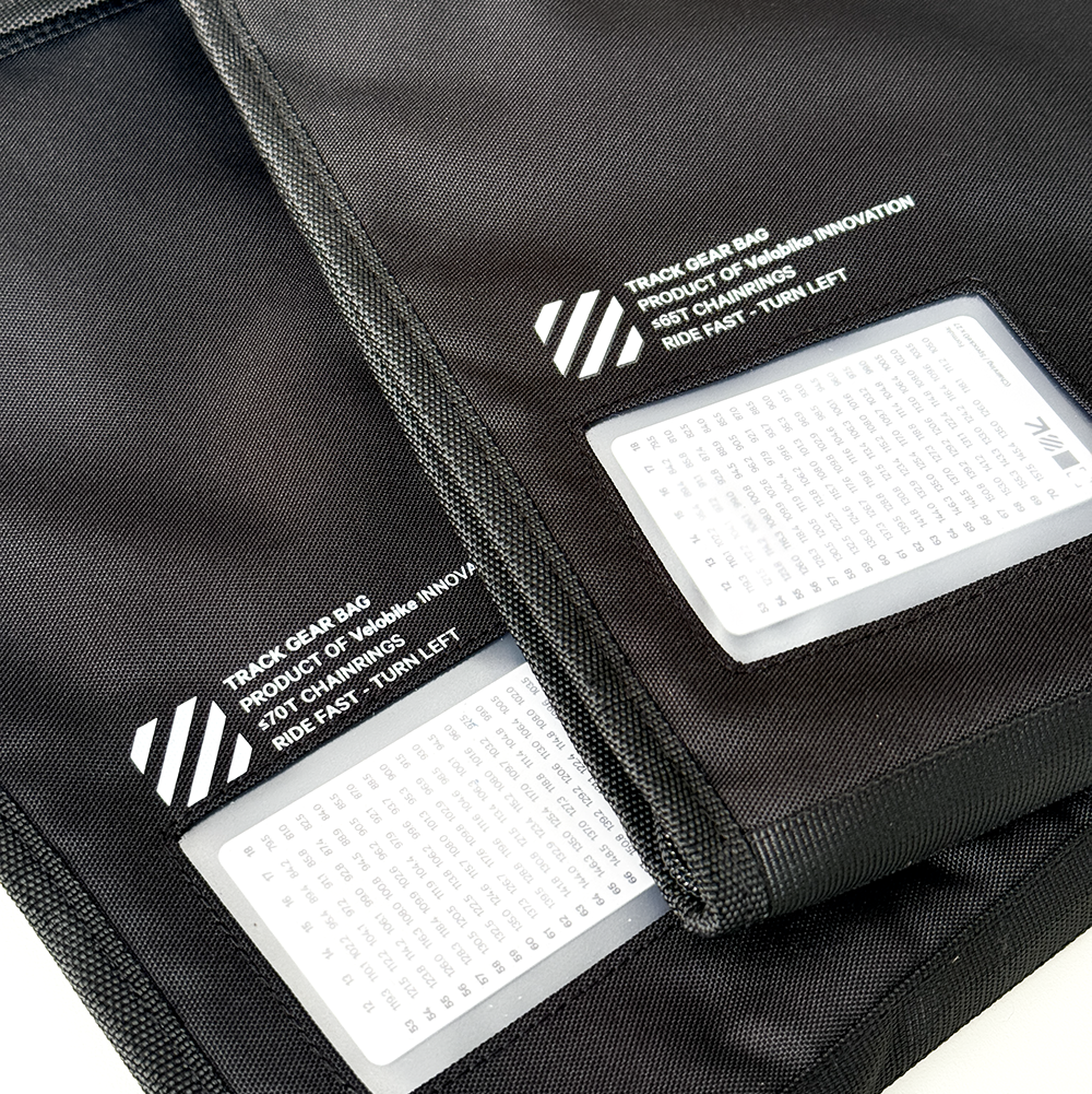 Black nylon track gear bag with two clear ID windows and white printed text, shown folded on a white background.